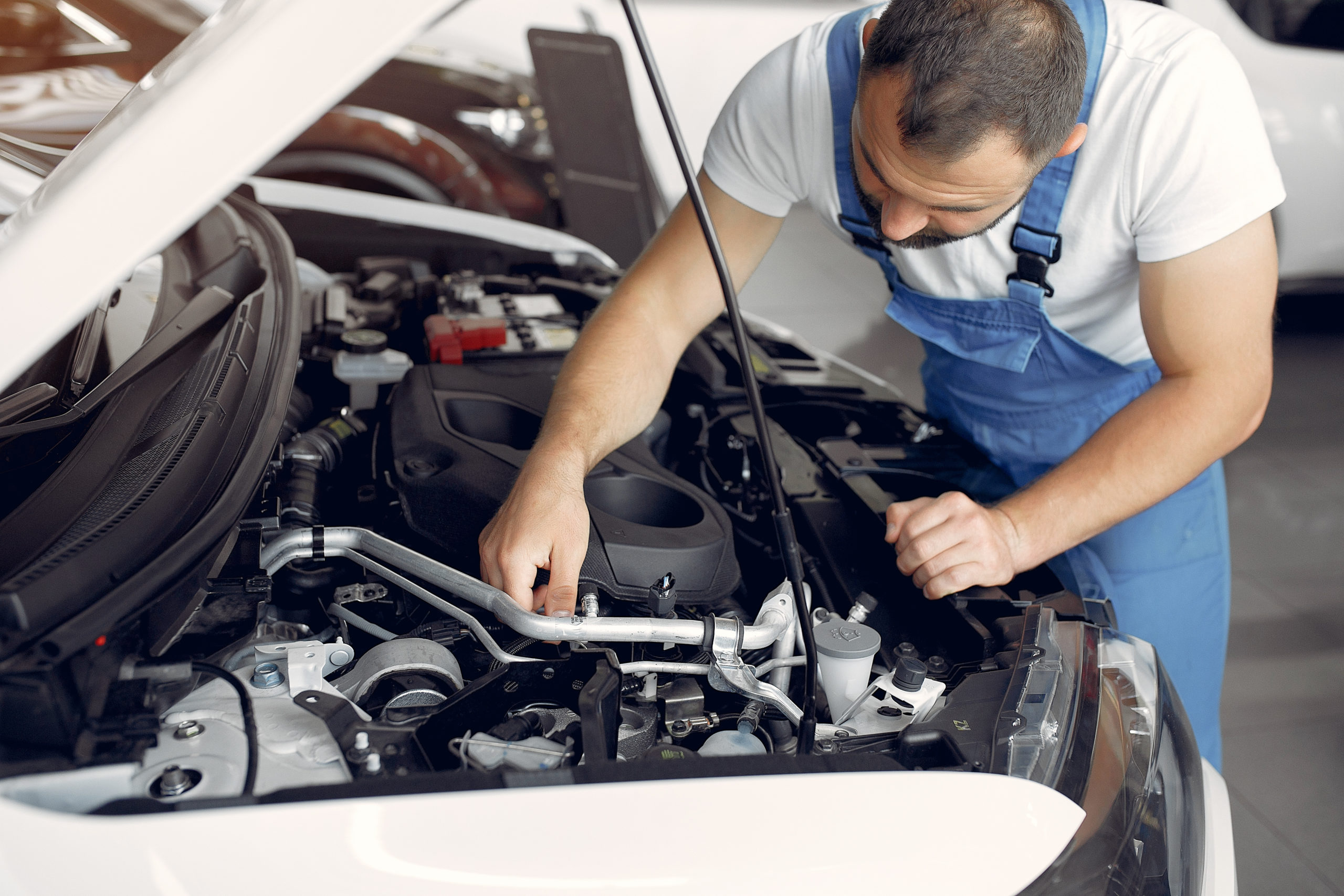 Mechanic in blue uniform inspecting a car