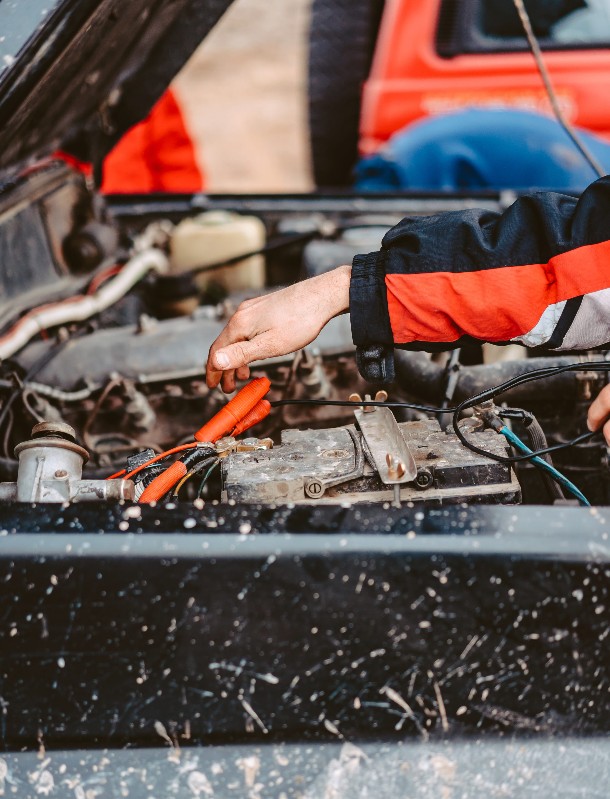 Mechanic jump-starting a dead car battery with jumper cables